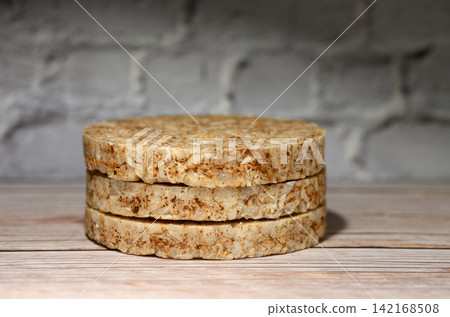 Stack of round rice cakes on a wooden surface against a white brick wall Stack of round rice cakes on a wooden surface against a white brick wall 142168508