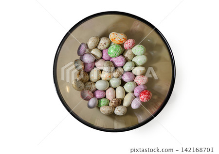 Top-down view of colorful speckled candy eggs in a glass bowl on a white background Top-down view of colorful speckled candy eggs in a glass bowl on a white background 142168701