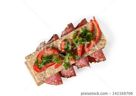 Top-down view of a gourmet crispbread sandwich with salami, red pepper, and herbs 142168706