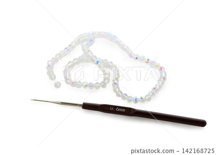 Delicate crafting session with shimmering beads and a precise crochet hook on a pristine surface Delicate crafting session with shimmering beads and a precise crochet hook on a pristine surface 142168725