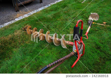 Landscape Drilling Tool Lies on the Grass After Work is Finished Landscape Drilling Tool Lies on the Grass After Work is Finished 142168918