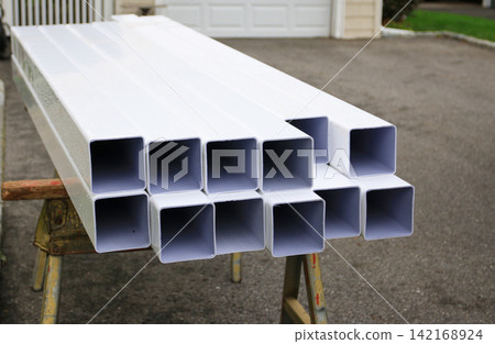 White Fence Posts Are Arranged on a Wooden Stand in a Driveway White Fence Posts Are Arranged on a Wooden Stand in a Driveway 142168924