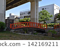 A riverside park and a red pedestrian bridge in Tokyo. 142169211