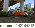 A riverside park and a red pedestrian bridge in Tokyo. 142169212