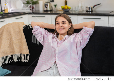 Young woman unwinds and rests takes slow breaths and finds calm posture with gentle smile and ease 142170018
