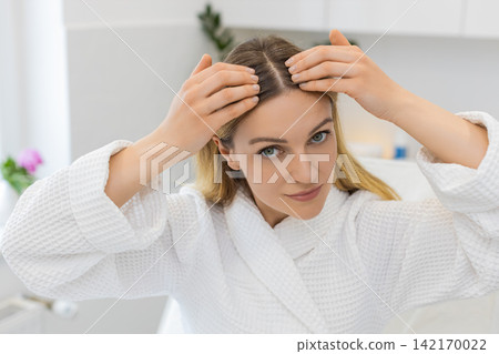 Caucasian young woman checking scalp and hair condition for alopecia signs in beauty clinic indoors Caucasian young woman checking scalp and hair condition for alopecia signs in beauty clinic indoors 142170022