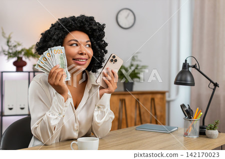 African American businesswoman happy holding dollars cash smartphone celebrates huge earnings budget African American businesswoman happy holding dollars cash smartphone celebrates huge earnings budget 142170023