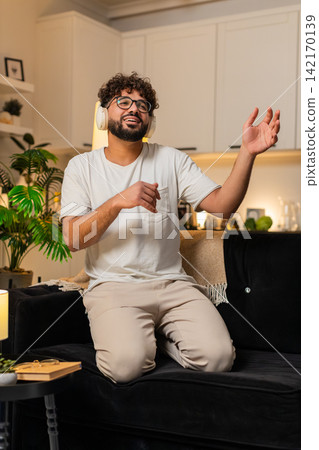 Arabian man plays air guitar dances rock n roll seated laughs energy fun music night indoors excited Arabian man plays air guitar dances rock n roll seated laughs energy fun music night indoors excited 142170139