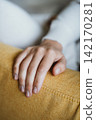 Hand Resting on Yellow Couch Displaying Relaxation 142170281