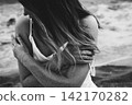 Pensive Woman with Sand-Covered Arms at Beach 142170282