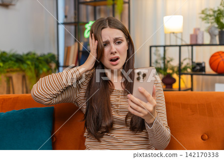 Young woman checks smartphone sees game loss sighs feels upset frowns after failed bet and bad news Young woman checks smartphone sees game loss sighs feels upset frowns after failed bet and bad news 142170338