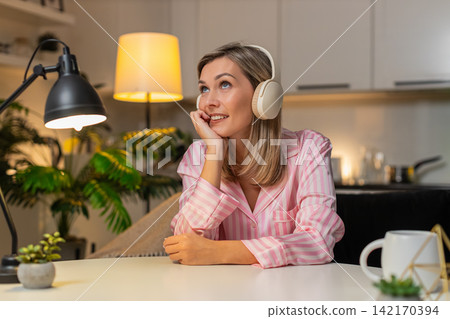 Adult woman in wireless headphones nods to music enjoys chill relax break calm evening vibes tonight Adult woman in wireless headphones nods to music enjoys chill relax break calm evening vibes tonight 142170394
