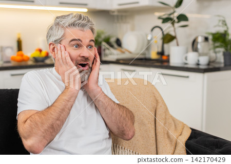 Middle-aged man grabs cheeks says wow happy surprise after positive good news joyful reaction Middle-aged man grabs cheeks says wow happy surprise after positive good news joyful reaction 142170429