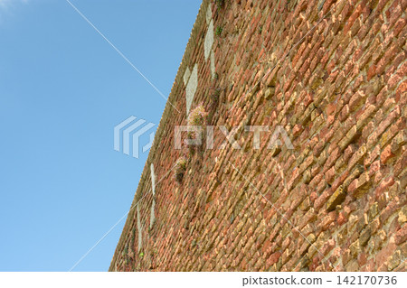 A weathered brick wall in a diagonal orientation under a clear blue sky A weathered brick wall in a diagonal orientation under a clear blue sky 142170736