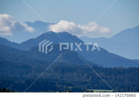 Cumulus clouds above the mountain ridge at the horizon. Vistara in the Gurktal valley, Carinthina, Austria, near Althofen. 142170868