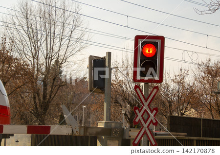 Train of the Austrian railroad company driving through a guarded railway crossing in Klagenfurth, Austria. Train of the Austrian railroad company driving through a guarded railway crossing in Klagenfurth, Austria. 142170878