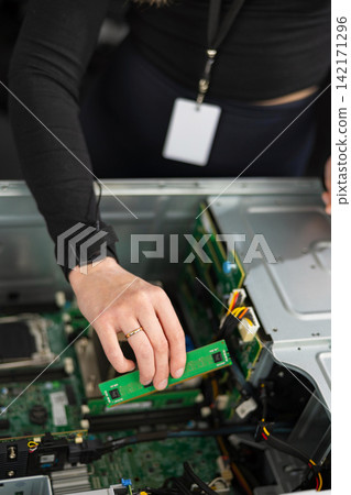 Female IT technician in her 30s upgrades a server with a new PCIe expansion card 142171296