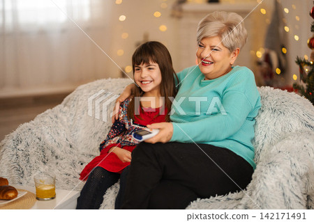 Grandmother and granddaughter watching TV together during holidays Grandmother and granddaughter watching TV together during holidays 142171491
