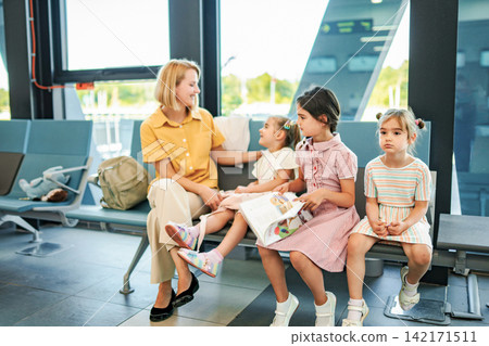 Mother and children waiting together in airport terminal Mother and children waiting together in airport terminal 142171511