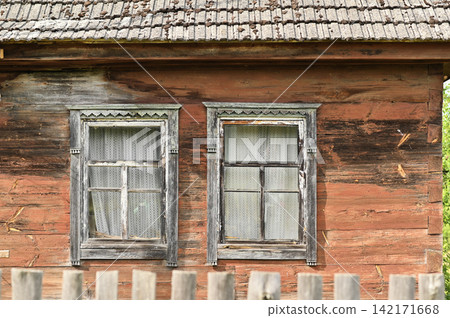 Wooden house stands with traditional carved window frames. Wooden house stands with traditional carved window frames. 142171668