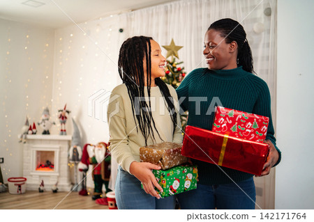 Happy multiracial mother daughter celebrating Christmas exchanging presents 142171764