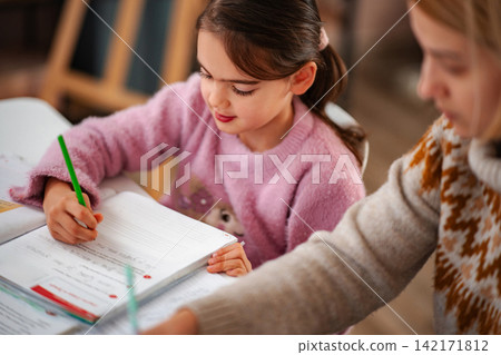 Little girl writing homework, learning with adult guidance Little girl writing homework, learning with adult guidance 142171812
