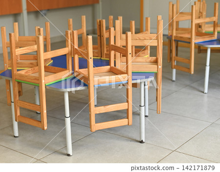 Empty classroom for kids with wooden chairs stacked on desks, Empty classroom for kids with wooden chairs stacked on desks, 142171879