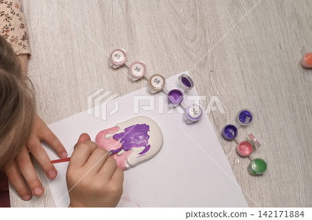 Small artist painting plaster ice cream toy using bright pink color. Small artist painting plaster ice cream toy using bright pink color. 142171884