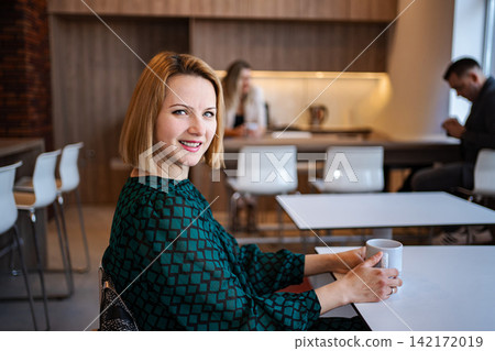 Smiling business woman having coffee break in office Smiling business woman having coffee break in office 142172019