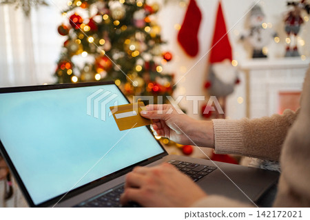 Woman holding credit card shopping online during Christmas holidays Woman holding credit card shopping online during Christmas holidays 142172021