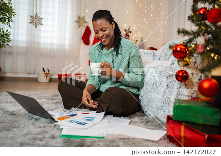 Woman remote working on laptop during Christmas holidays Woman remote working on laptop during Christmas holidays 142172027
