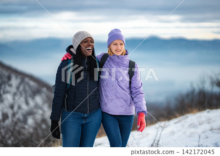 Diverse female friends enjoying winter hiking in snowy mountains Diverse female friends enjoying winter hiking in snowy mountains 142172045
