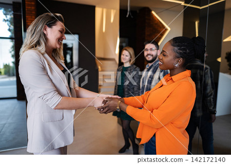 Businesswomen shaking hands in modern office greeting new partner Businesswomen shaking hands in modern office greeting new partner 142172140