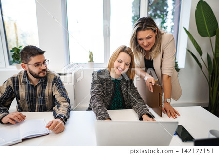 Business team collaborating on project using laptop in office Business team collaborating on project using laptop in office 142172151