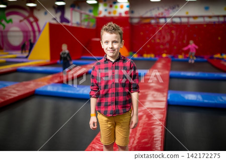 Boy standing on a safety mat at a trampoline park Boy standing on a safety mat at a trampoline park 142172275