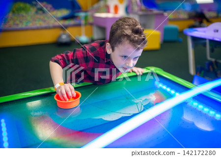 Boy playing air hockey in an amusement center Boy playing air hockey in an amusement center 142172280