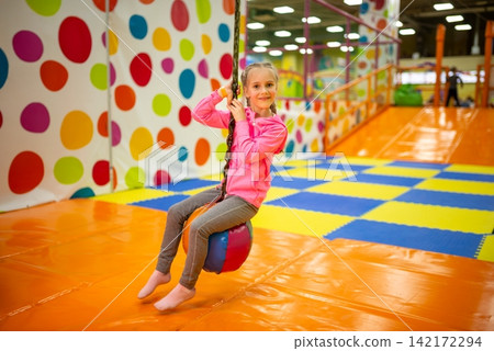 Happy girl riding a dynamic indoor zip line swing Happy girl riding a dynamic indoor zip line swing 142172294