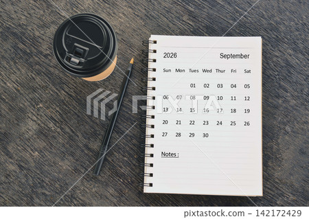 September 2026 desk calendar with disposable coffee cup and pen on wooden table. Directly above. Flat lay 142172429