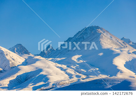 Majestic Snowy Mountain Range Under Clear Blue Sky Majestic Snowy Mountain Range Under Clear Blue Sky 142172676
