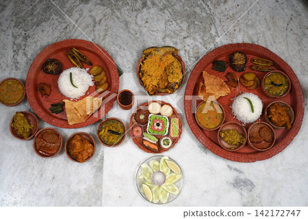 Grand spread of traditional Bengali feast with multiple thalis sweets and curries served on marble floor Grand spread of traditional Bengali feast with multiple thalis sweets and curries served on marble floor 142172747