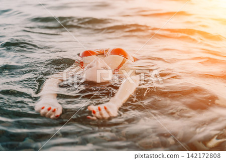Woman floating water, serene young woman relaxing on her back in ocean at golden hour, summer vacation. Woman floating water, serene young woman relaxing on her back in ocean at golden hour, summer vacation. 142172808