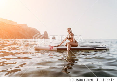 Woman Paddleboard Ocean Relaxing on Paddleboard in Sea at Sunset Woman Paddleboard Ocean Relaxing on Paddleboard in Sea at Sunset 142172812