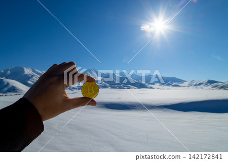 Hand Holds Bitcoin Coin in Snowy Kyrgyzstan Landscape Hand Holds Bitcoin Coin in Snowy Kyrgyzstan Landscape 142172841
