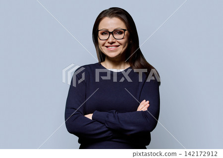 Smiling 40s mature woman in glasses with arms crossed studio portrait Smiling 40s mature woman in glasses with arms crossed studio portrait 142172912
