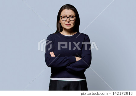 Serious 40s mature woman in glasses with arms crossed studio portrait Serious 40s mature woman in glasses with arms crossed studio portrait 142172913