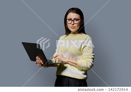 Confident mature woman in glasses holding laptop looking at camera portrait 142172914