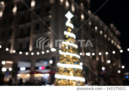Christmas Tree with Twinkling Lights and Festive Bokeh in Modern City 142173021