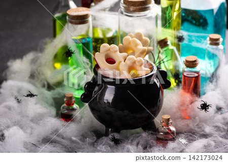 Halloween cauldron filled with ghost shaped cookies surrounded by spooky potions and cobwebs Halloween cauldron filled with ghost shaped cookies surrounded by spooky potions and cobwebs 142173024
