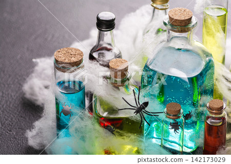 Collection of spooky Halloween potion bottles with cobwebs and spiders, atmospheric lighting, festive holiday concept Collection of spooky Halloween potion bottles with cobwebs and spiders, atmospheric lighting, festive holiday concept 142173029