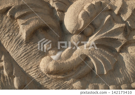 Intricate stone carving of a mythical dragon face in soft sunlight Intricate stone carving of a mythical dragon face in soft sunlight 142173410